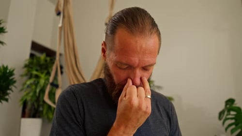 a yogi man with a beard performs breathing practices through the nose during meditation