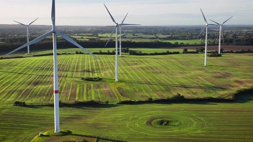 Aerial footage of wind farm with large spinning wind turbines. Aerial flying over renewable energy w