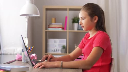 Teen Typing on Laptop at Desk in Bedroom