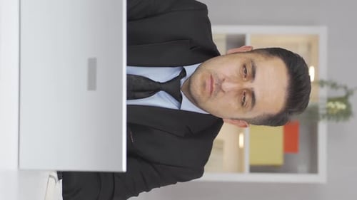 Vertical video of Home office worker man looking at camera depressed.