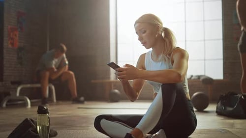 Woman Using Phone in Gym After Workout