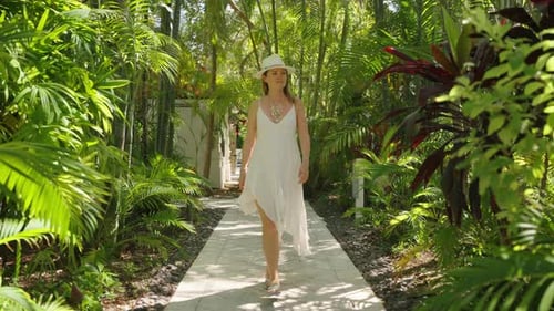 A Woman Strolls Leisurely in a Lush Hotel Garden in Key West Florida