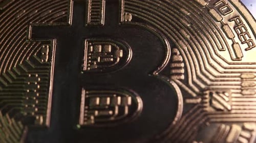 Pièce cryptographique 4K en monnaie Bitcoin tournant lentement dans le sens des aiguilles d'une montre avec une lumière réfléchissante sur fond noir
