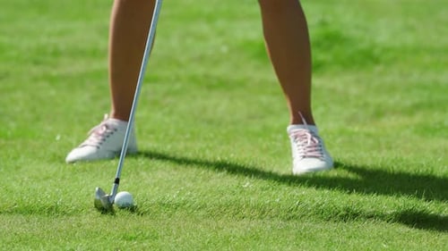 A Golfer Stands on Green and Hits a Ball with a Golf Club