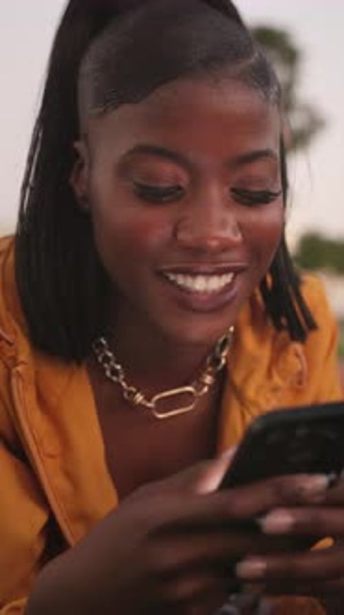 Young, black woman and smartphone outdoor, happy with meme online and chat, relax and check post