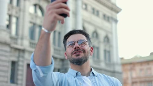 Man Video Calling on Phone in Urban Setting