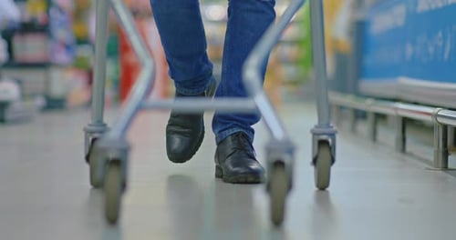 Feet of Male Customer in Supermarket Closeup Man Rolling Shopping Cart in Trading Area Prores