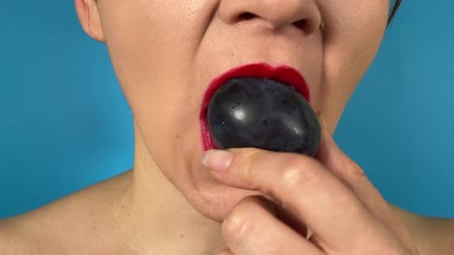 Nahaufnahme weiblicher Mund, farbige Lippen, isst reife Früchte, isolierter Hintergrund