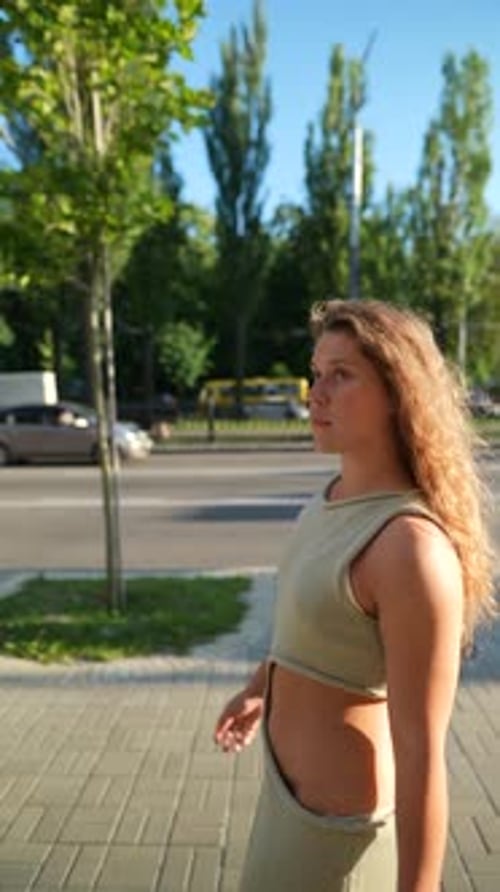 Woman Walking on Urban Sidewalk in Stylish Outfit