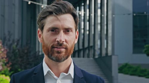 Smiling Man in Suit Stands in Front of Building