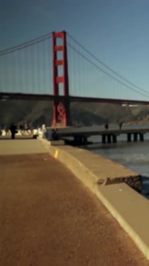 Caméra panoramique à droite révélant la tour du pont à gauche, les visiteurs filmant la jetée et l'eau à des fins touristiques