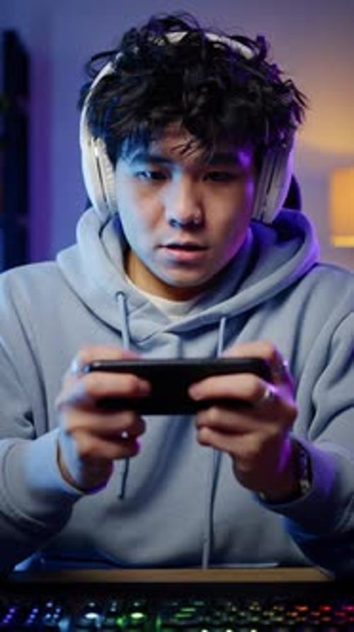 Enthusiastic Young Man Plays Game on Mobile Phone
