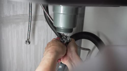 Professional Plumber Tightening Siphon Drain Pipe Connections Under Kitchen Sink Working with