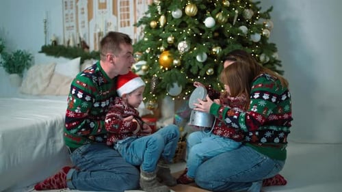 The Family Opens Presents Together Under the Christmas Tree at Home