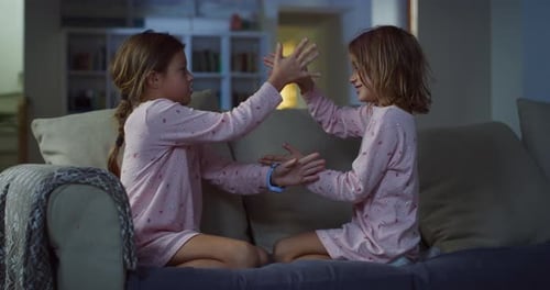 Portrait of Two Female Siblings Doing a Rock-Scissors-Paper Game While Smiling and Laughi