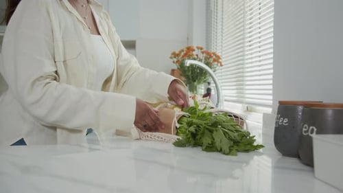 Ama de casa anónima sacando alimentos frescos del mercado de una bolsa de malla