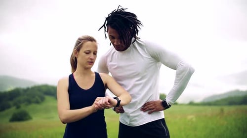 Athletic Couple Checking Smartwatch After Exercise Outdoors