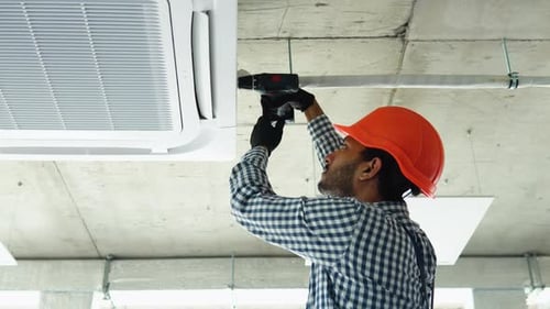 Indian Young Worker Installs Air Conditioner in the Office