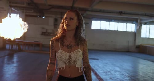 Woman with Tattoos Poses with Flames Indoors
