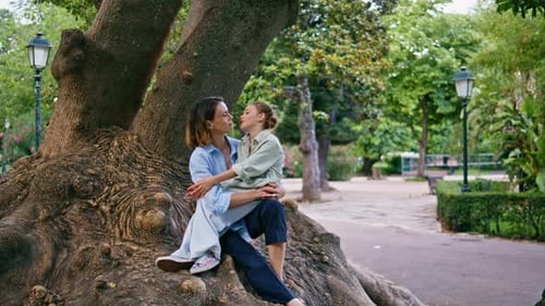 Mother and Daughter Cuddle at Base of Tree