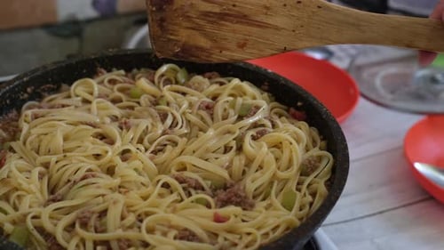 Stirring Linguine with Meat Sauce in Kitchen