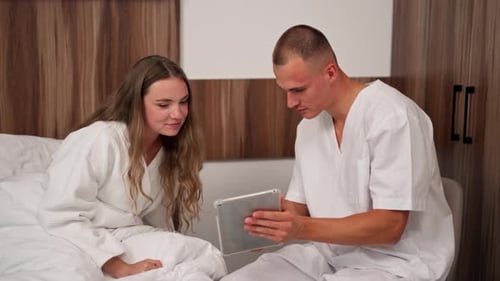 in Modern Clinic in a Bright VIP Room a Young Girl in a White Coat Lies on the Bed Consulting a