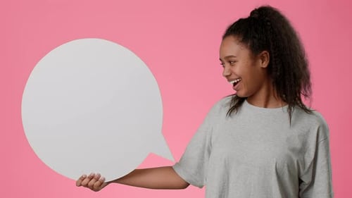 Teen Girl Joyfully Holding a Speech Bubble Against a Pink Background