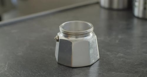 Primer plano de la preparación de café con una moka. La mano junta las piezas y llena el filtro con f