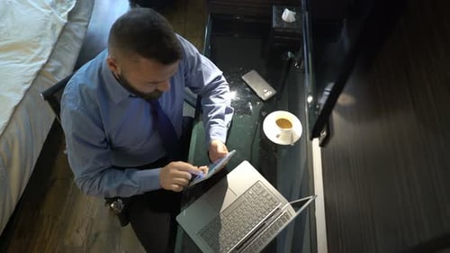 Young businessman browsing web on tablet computer in modern hotel room