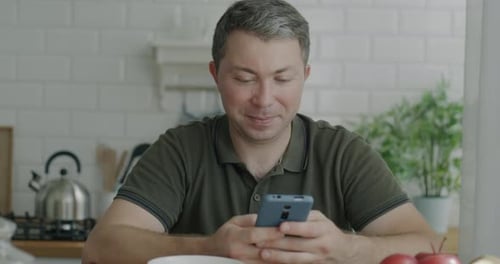 Man Using Smartphone in Bright Kitchen
