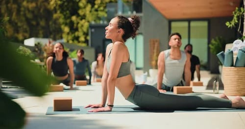 Yoga Class Performs Cobra Pose on Sunny Patio