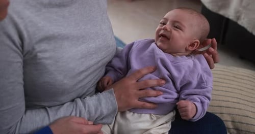 Smiling Baby Being Held by Two Women Indoors