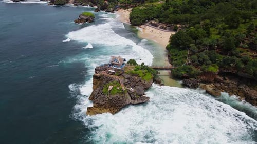 Aerial view of coral island on the beach hits by the wave. Orbit drone shot - Kukup Beach, Yogyakart