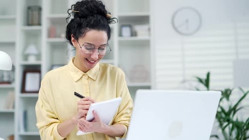 Woman in Online Meeting Taking Notes