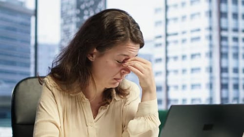 Stressed Woman Working at Computer in City Office