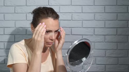 Woman Examining Face in Mirror Close Up