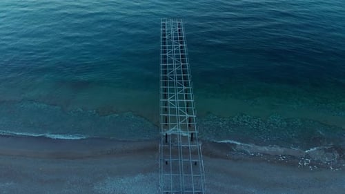 La caméra descend au-dessus de l'ancienne charpente de la jetée maritime en métal