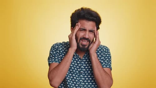 Young Man Rubbing Temples in Discomfort