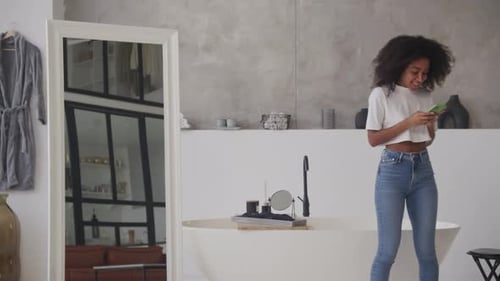 Young Woman Texting in Modern Bathroom