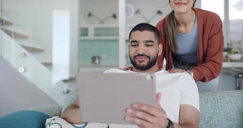 Smiling Couple Using Tablet Together on Sofa at Home