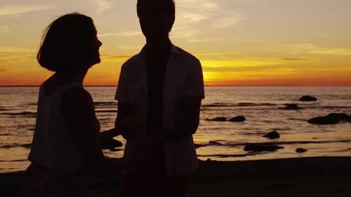 Couple is Dancing on the Beach in Sunset Time.