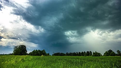 Powerful storm clouds flowing above rural landscape, time lapse view