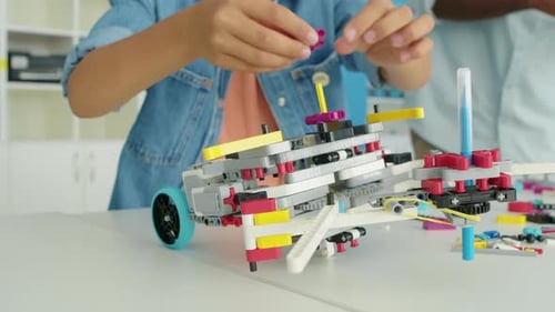 Hände eines anonymen Kindes bauen eine Struktur aus Spielzeugplastikblöcken