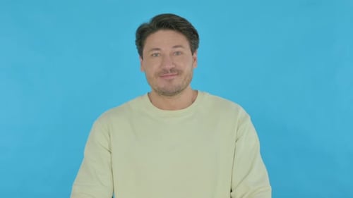 Dark Haired Man Talking in front of Blue Background