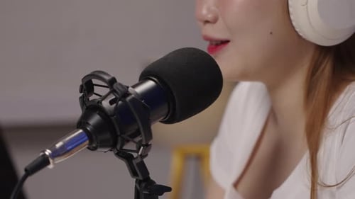 Close up shot of podcast host speaking into microphone during live recording.