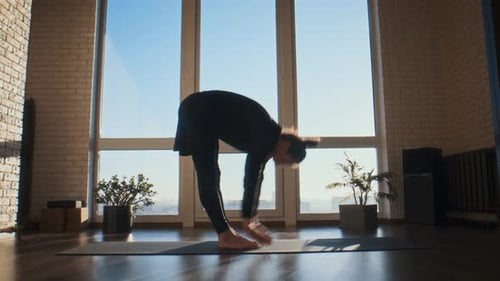 Un hombre alegre se inclina hacia atrás sobre una colchoneta de yoga en el estudio