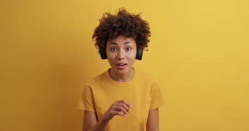 Excited young woman listens with headphones in studio