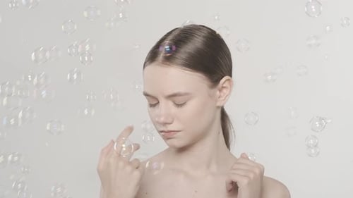 Woman Surrounded by Floating Bubbles in a Studio
