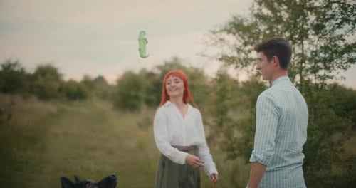 Loving Couple Embraces in Field with Black Dog
