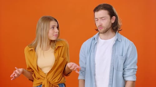 Young Couple Arguing with Orange Background